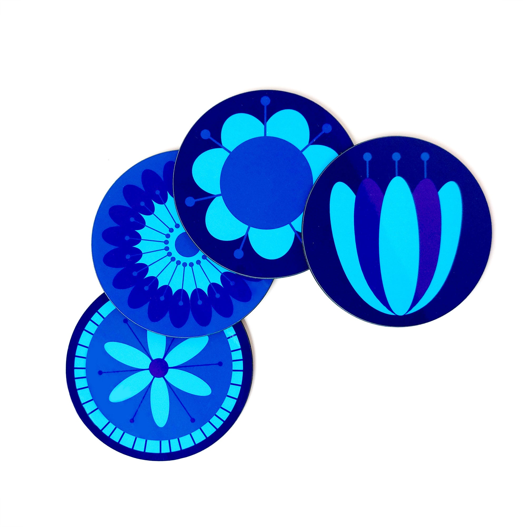 Four round coasters featuring retro style flowers in blues & purples lie on a white table | The Inkabilly Emporium
