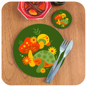 Round 70s style placemat and matching coaster featuring a retro mushrooms design sits on a teak table with mid century cutlery, accompanied by a couple of vintage pottery pieces | The Inkabilly Emporium