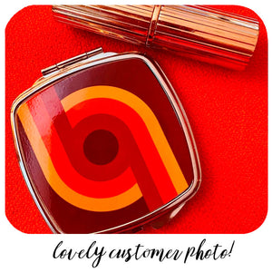 Customer photo of 70s Supergraphic compact mirror with lipstick on a red background | The Inkabilly Emporium