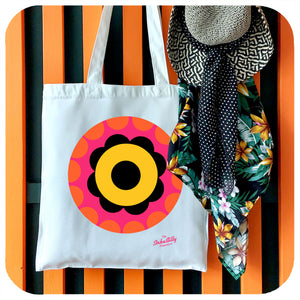 A canvas tote bag with a bright floral motif in 60s style hangs on a coat rack with a straw sun hat and tropical scarf | The Inkabilly Emporium
