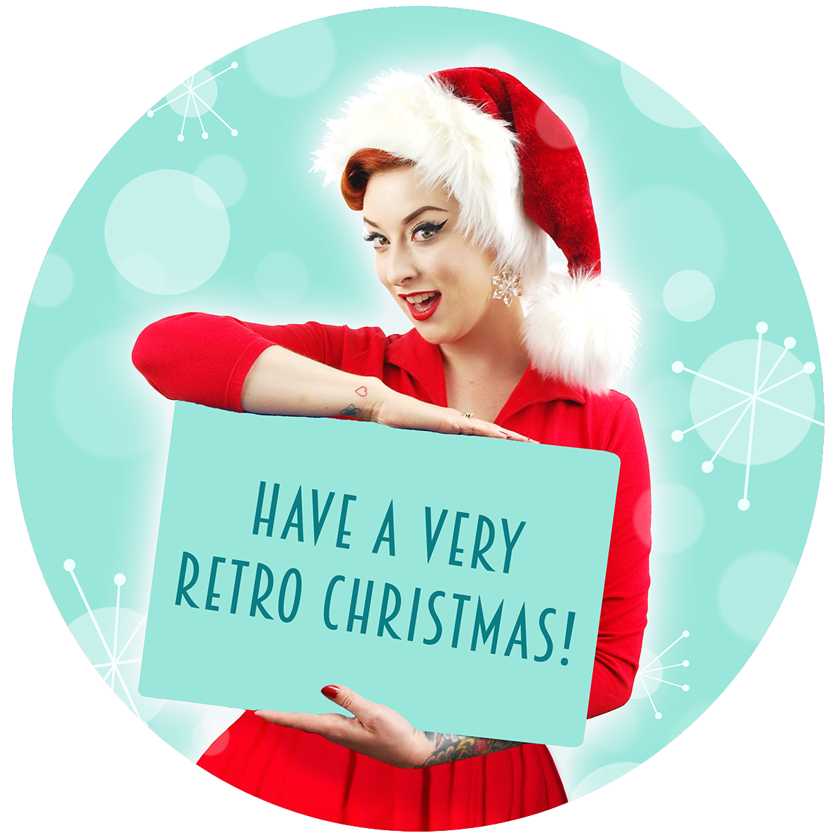 A young woman in a Santa hat and red dress holds up a sign which reads - Have a very retro Christmas! | The Inkabilly Emporium