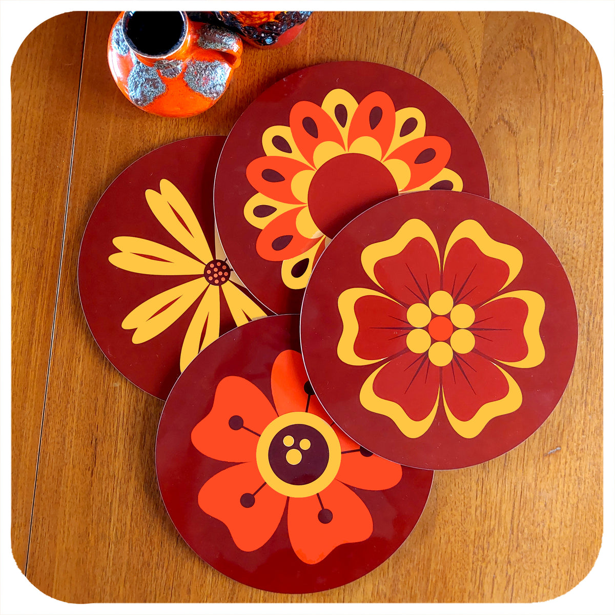 A set of four round 70s floral placemats on teak table with fat lava vases | The Inkabilly Emporium