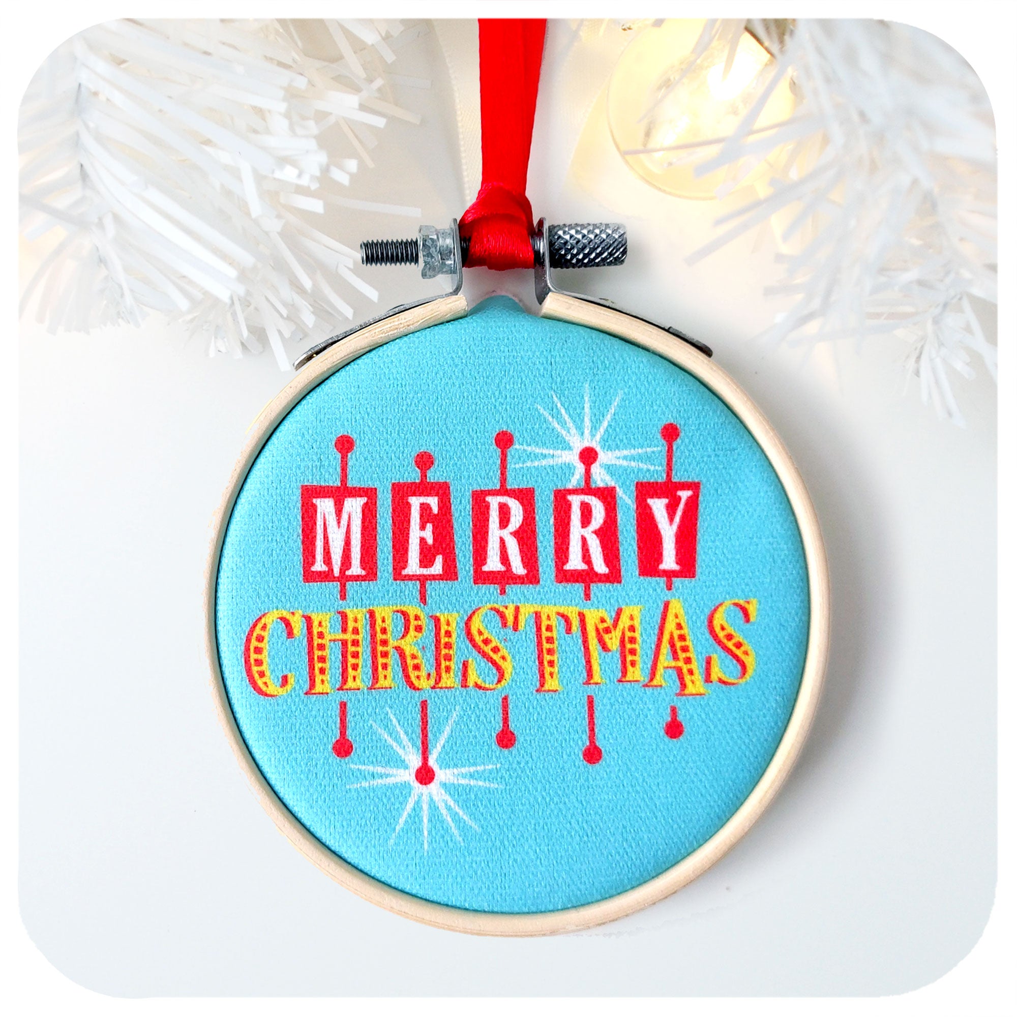 A printed fabric Christmas tree decoration in the style of a vintage las vegas sign on a white background with white christmas tree branch and fairy light | The Inkabilly Emporium
