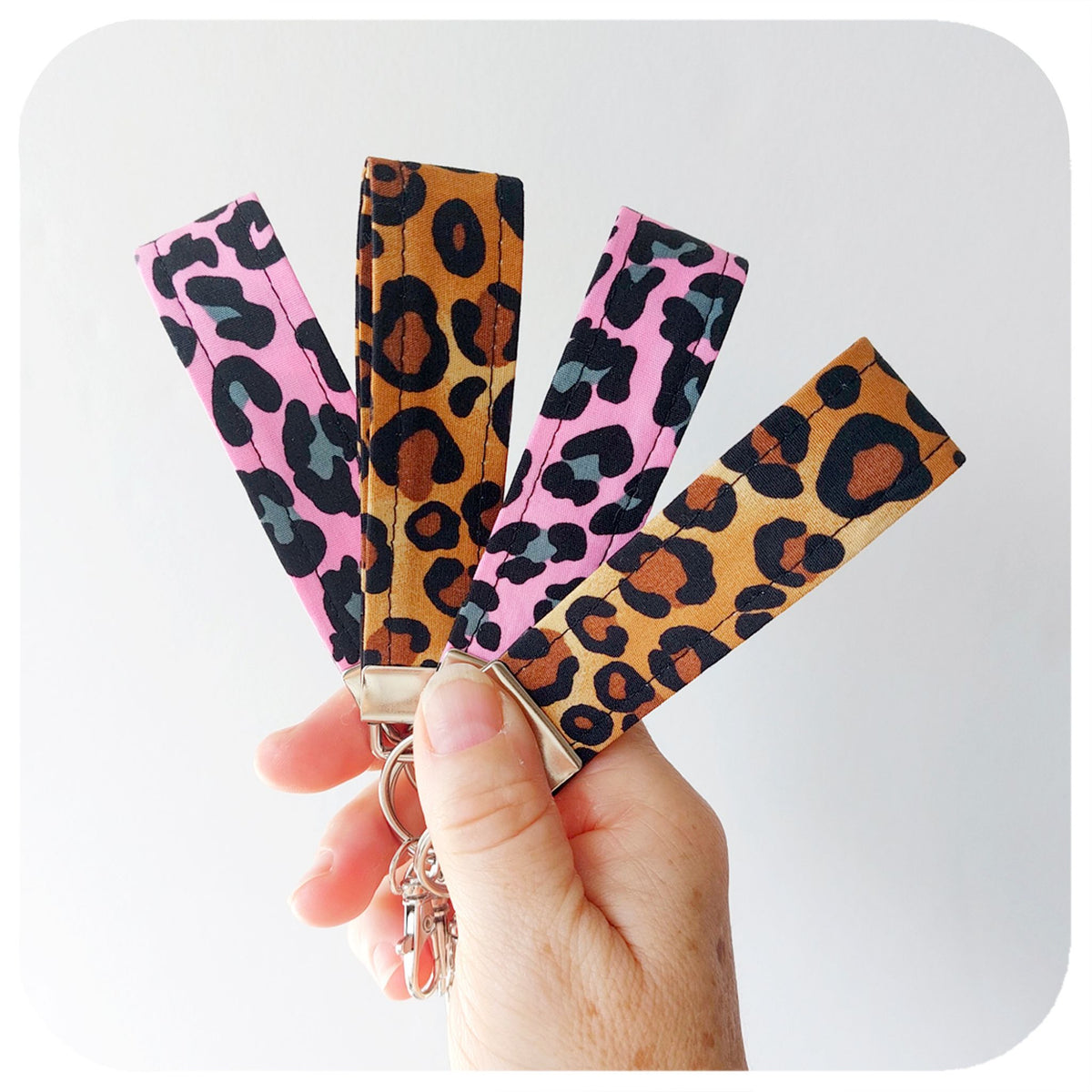 Hand holding a keychain with leopard print straps on a white background | The Inkabilly Emporium