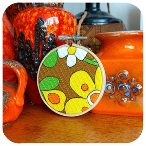 Embroidery hoop with floral design in front of orange ceramic pots