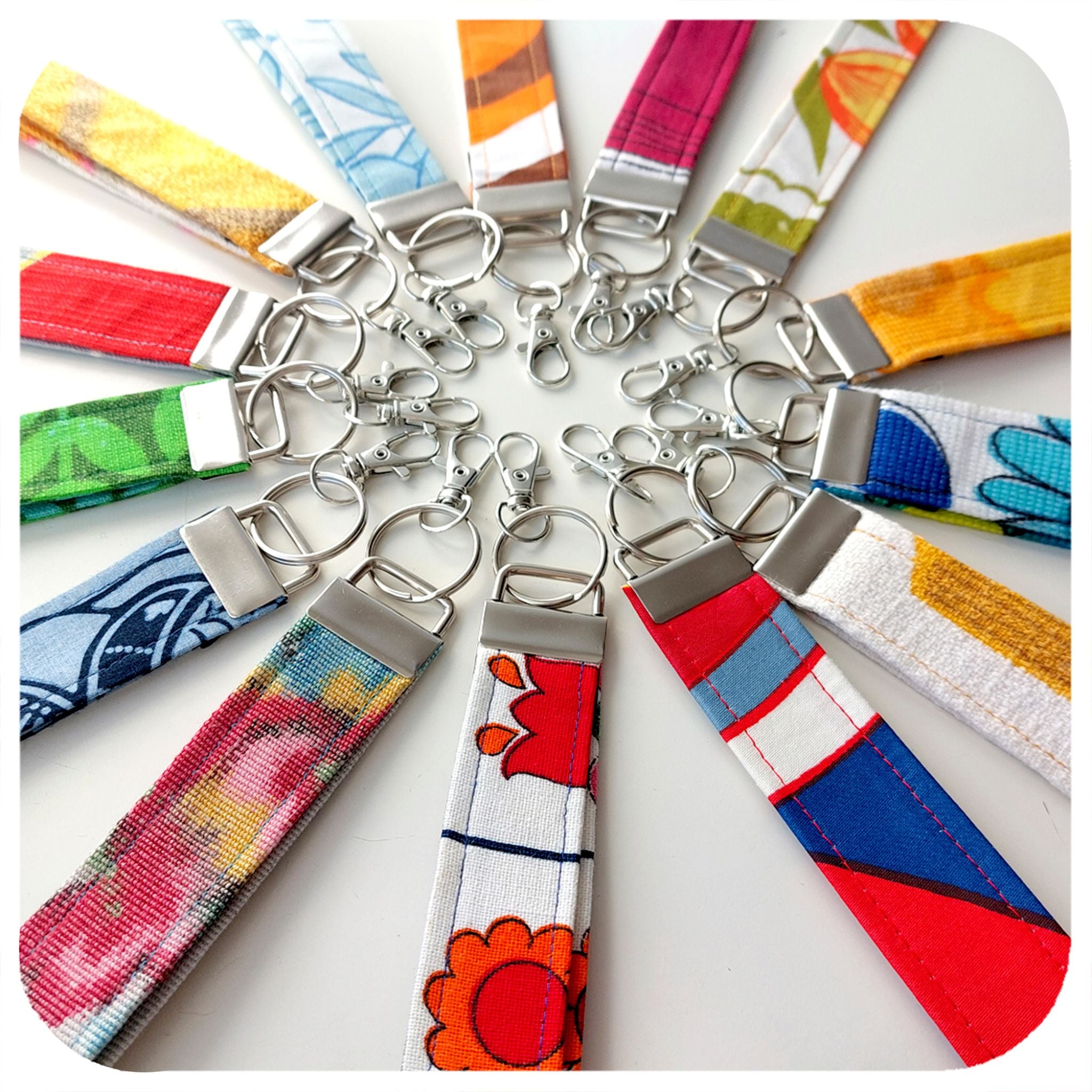 Colourful keychains with floral patterns arranged in a circular pattern on a white background.