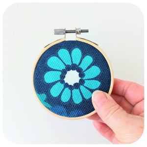 Embroidery hoop with floral design held against a white background