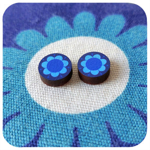 Blue flower-shaped earrings on a blue and white floral background