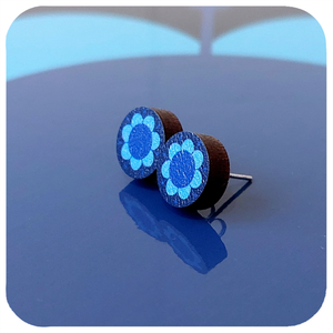 Blue flower-shaped earrings on a reflective blue surface