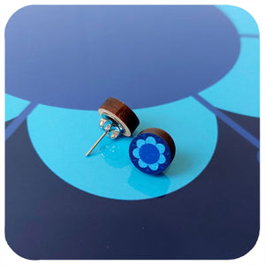 Wooden earrings with blue floral design on a blue abstract background