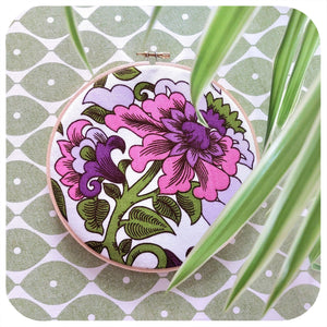 Embroidery hoop with floral design on a green and white patterned background