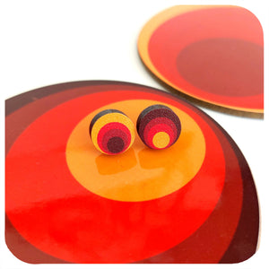Colourful circular earrings on a matching red and orange background