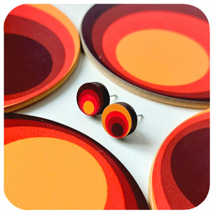 Colourful circular earrings on a white background surrounded by matching coasters
