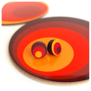 Colourful circular earrings on a matching disc with concentric red, orange, and yellow rings.