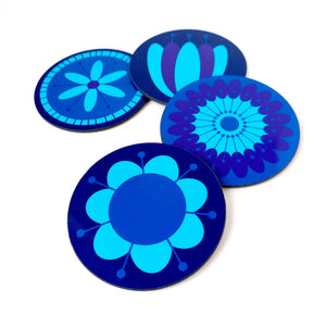 Four round coasters featuring retro style flowers in blues & purples on a white table | The Inkabilly Emporium