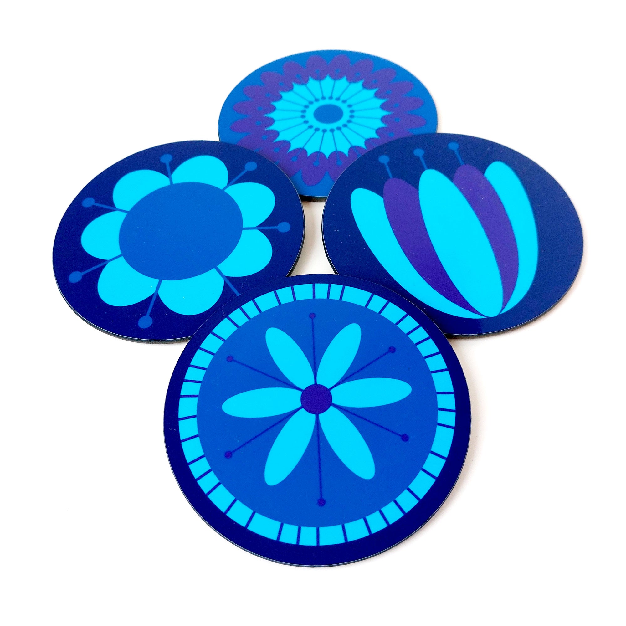 Four round coasters featuring retro 70s style flowers in blues & purples lie on a white table | The Inkabilly Emporium
