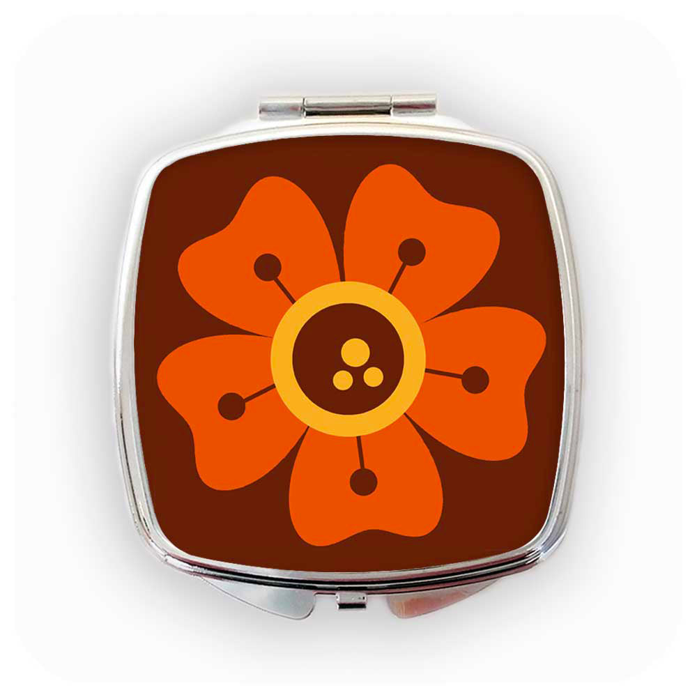 A chrome compact mirror with a 70s style retro flower design in orange and brown on the front sits on a white background | The Inkabilly Emporium