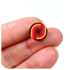 Small circular stud earring with red and yellow design held between fingers on a white background  | The Inkabilly Emporium