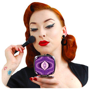 A retro pin-up model applies make-up while looking into a 70s style compact mirror | The Inkabilly Emporium