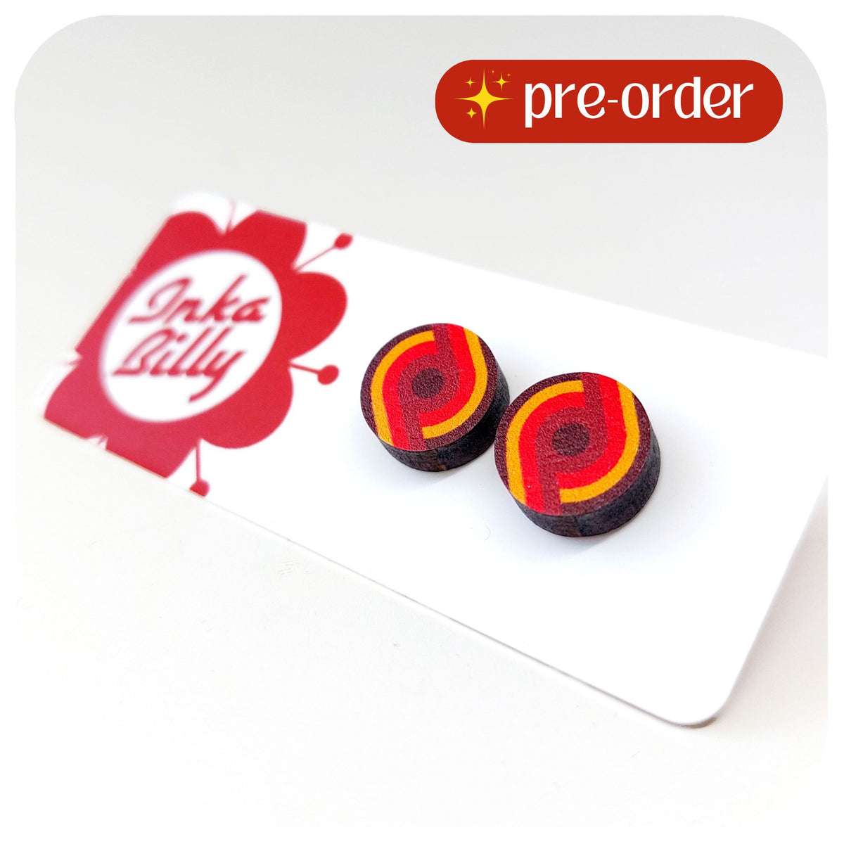 Pair of round earrings with red and yellow design on a white card with 'InkaBilly' branding. Text in top right corner reads: Pre-order