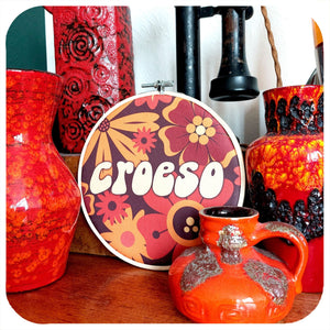 Decorative items including vases and a fabric hoop with 'Croeso' text on a wooden surface.