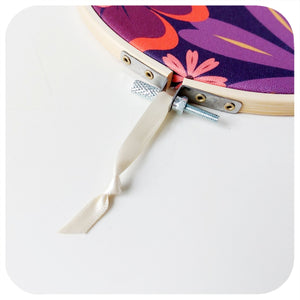 Embroidery hoop with floral fabric and cream rbbon on a white background