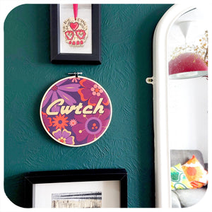 Decorative hoop with floral pattern and 'Cwtch' text on a green wall