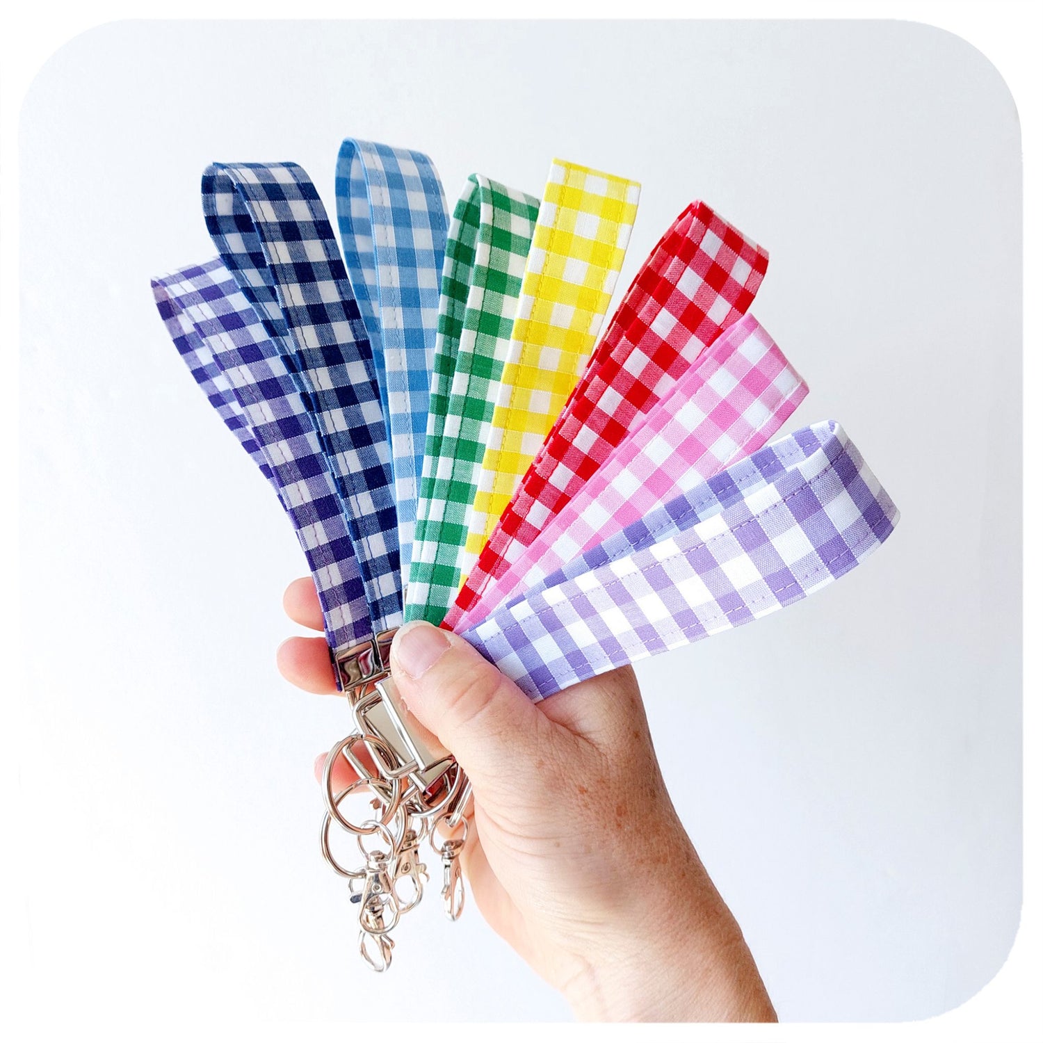 Set of colourful plaid keychains held by a hand against a white background