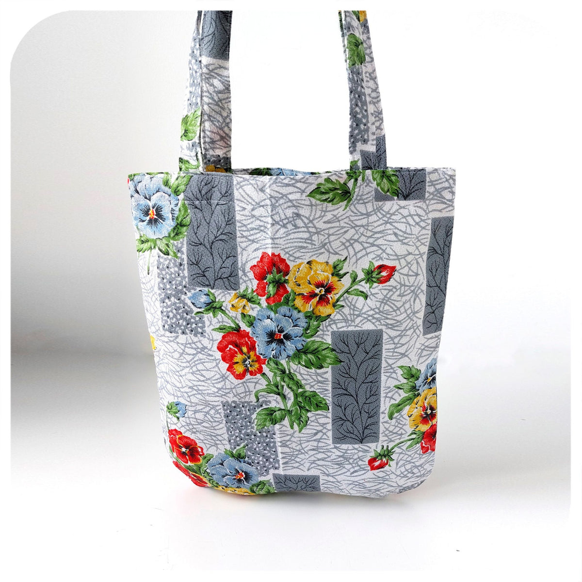 Floral tote bag with colorful flowers on a gray patterned background
