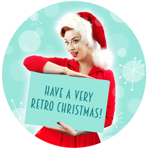 A young woman in a Santa hat and red dress holds up a sign which reads - Have a very retro Christmas! | The Inkabilly Emporium