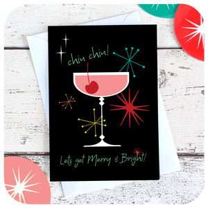 Chin chin! Let's Get Merry & Bright! Mid century style Christmas card with white envelope on a white wood table surrounded by vintage style xmas decorations | The Inkabilly Emporium