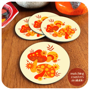 A set of four round vintage style mushroom coasters sit on a teak table with vintage pottery pieces in the background. Text in the corner reads "matching coasters available" | The Inkabilly Emporium