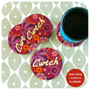 Floral coasters with 'Cwtch' text on a matching coaster set, featuring a cup of coffee.