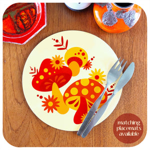 Round 70s style mushroom placemat with knife and fork on a teak table surrounded by various mid century vintage pottery pieces. Text in corner reads: matching placemats available | The Inkabilly Emporium