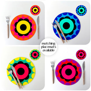A photo montage of Inkabilly's 60s flower power placemats. Four different coloured round placemats with matching coasters on white backgrounds. Text in the middle reads: matching placemats available.