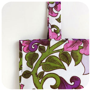 Floral patterned fabric with pink and green design on a white background - Close up.