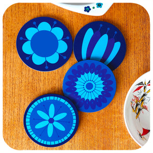 Four round coasters featuring retro style flowers in blues & purples sit next to a vintage dishes on a teak table | The Inkabilly Emporium