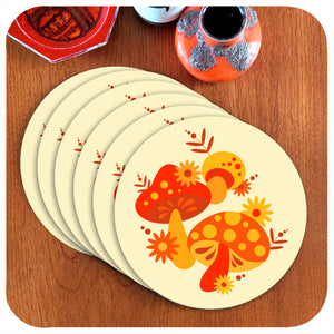 A set of six Round Retro Mushrooms Placemats lie in an overlapping line on a teak table next to vintage pottery pieces | The Inkabilly Emporium