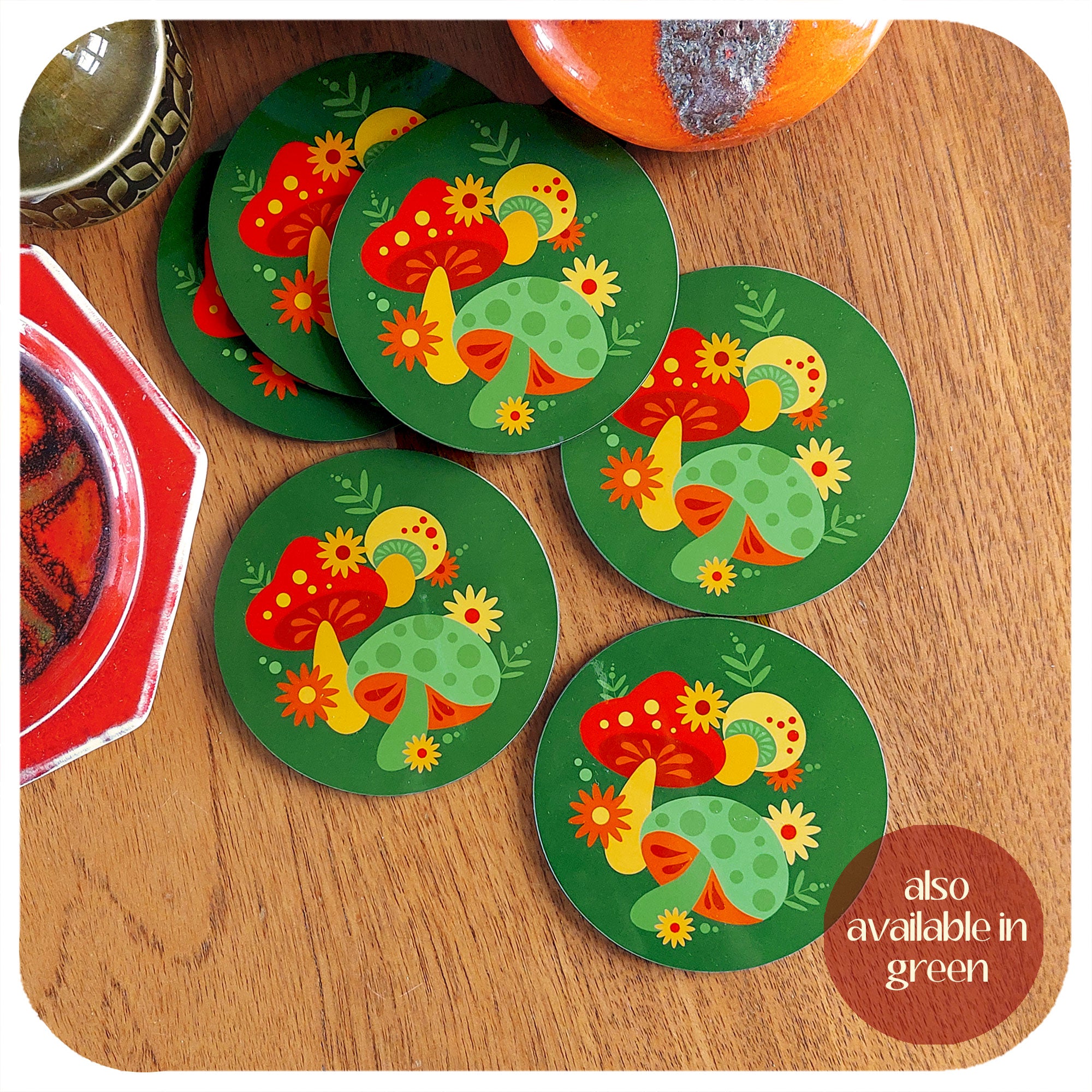A set of 6 green 70s style coasters lie in a scattered pile on a teak table. Text in the lower right hand corner reads: also available in green | The Inkabilly Emporium