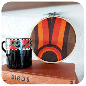 Framed vintage fabric hoop in 70s graphic sits on a stack of vintage books with a vintage espresso mug | The Inkabilly Emporium
