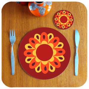 A single round 70s floral placemat on teak table with coaster and cutlery, fat lava vase | The Inkabilly Emporium