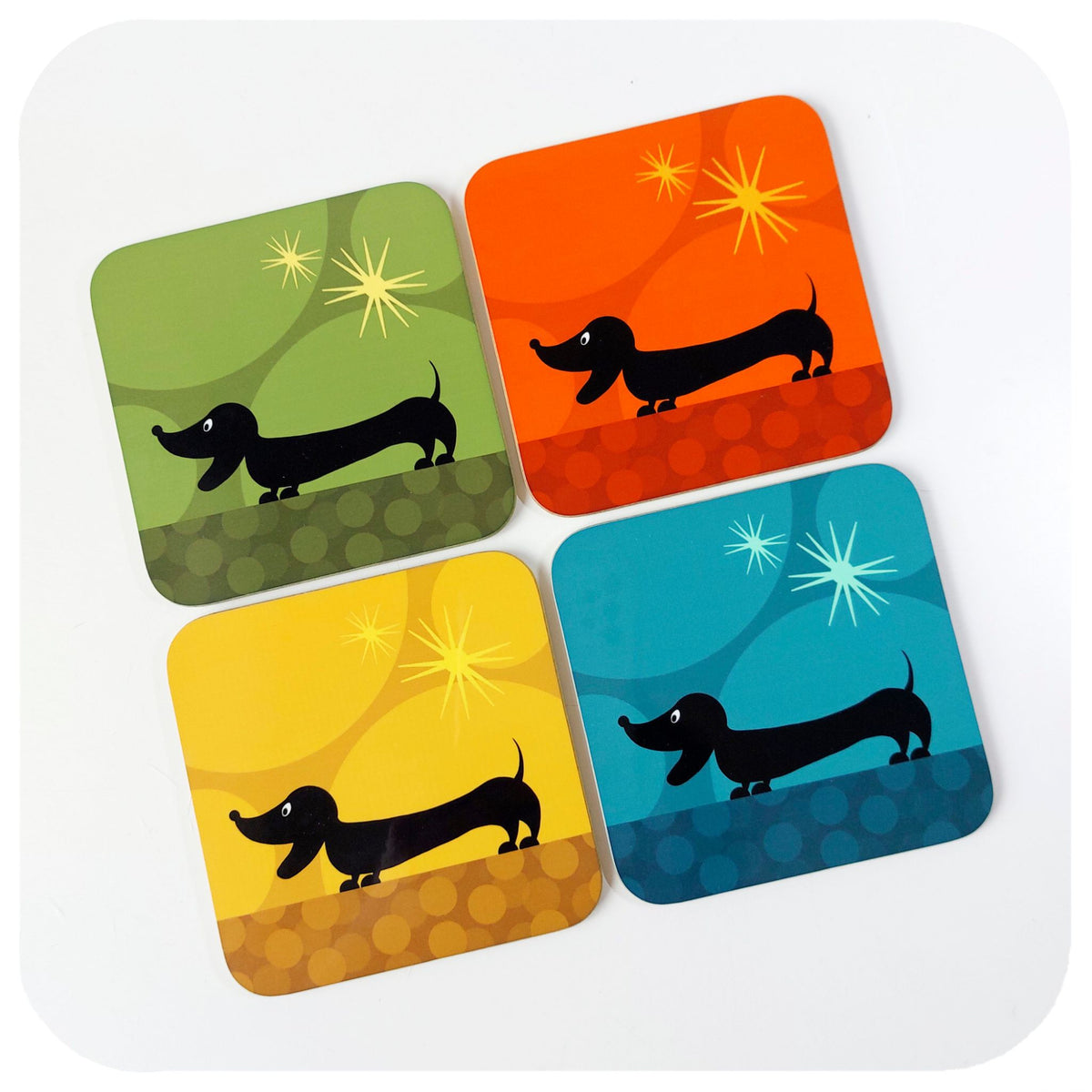 Four colourful coasters with dachshund illustrations on a white background