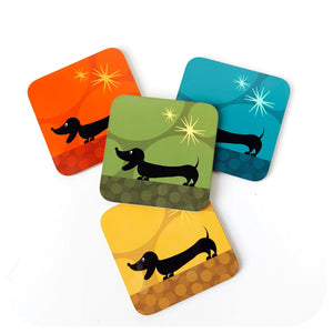 Four colourful coasters with dachshund illustrations on a white background