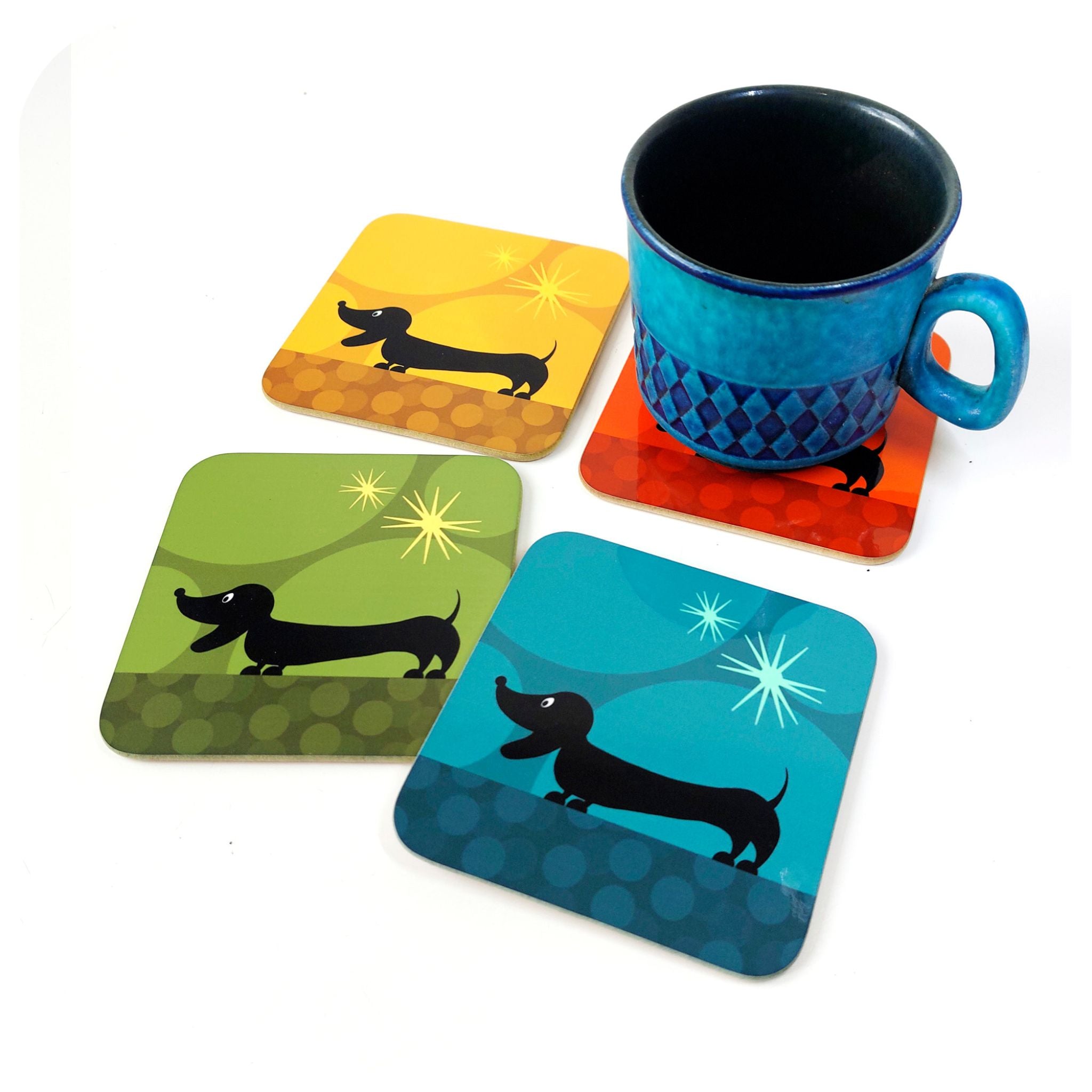 Set of four colourful coasters with dachshund designs and a blue mug on a white background
