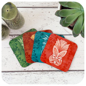 Set of four Tiki coasters in various colours on a white wooden table with  tiki cruet set and potted plant | The Inkabilly Emporium