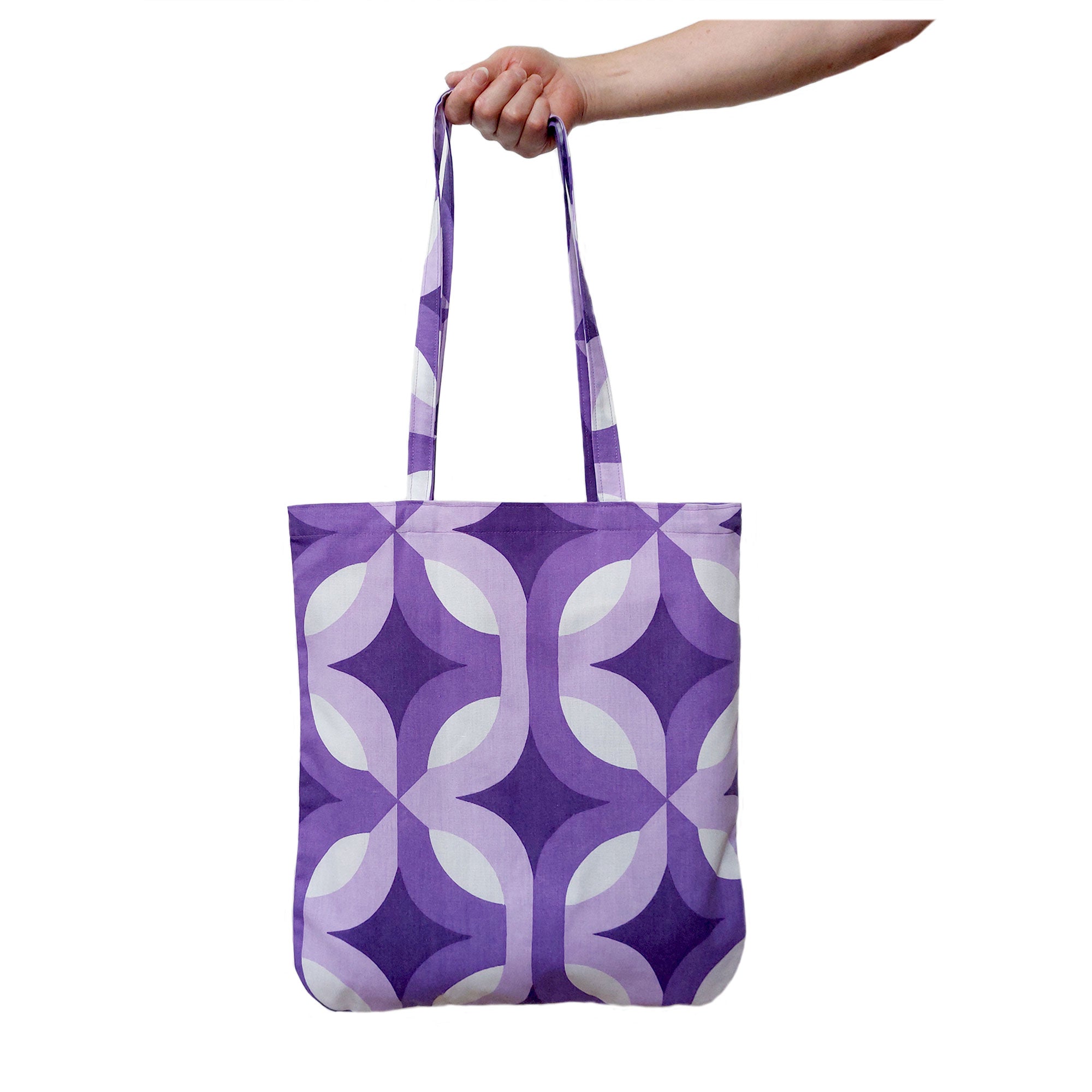A handmade tote bag, made from vintage 70s fabric, with an Op Art pattern in purple & white, is held against a white backgound | The Inkabilly Emporium