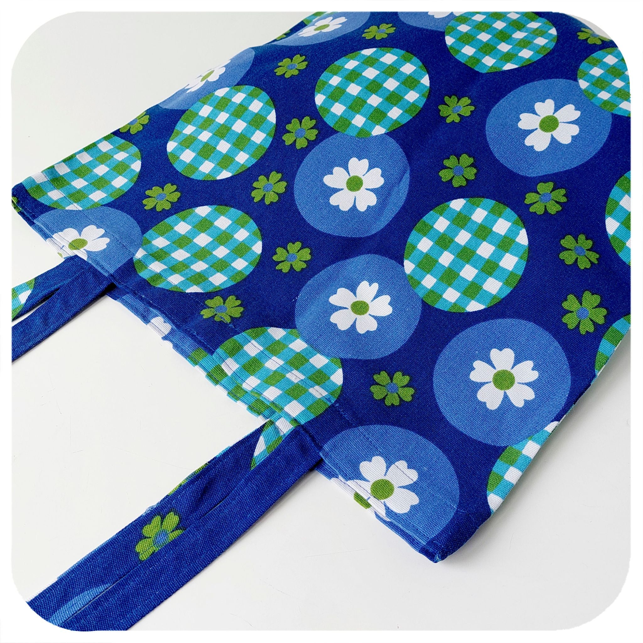 Blue vintage fabric tote bag with floral and checkered patterns on a white background