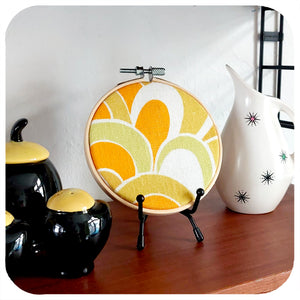 A framed vintage fabric hoop is displayed on a shelf with vintage kitchenware | The Inkabilly Emporium