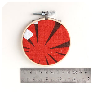 A Vintage Fabric Embroidery Hoops on a white background with a ruler to show scale