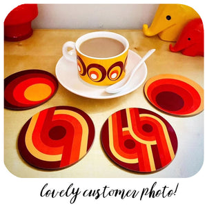 Set of colourful coasters with a cup and saucer on a wooden surface.